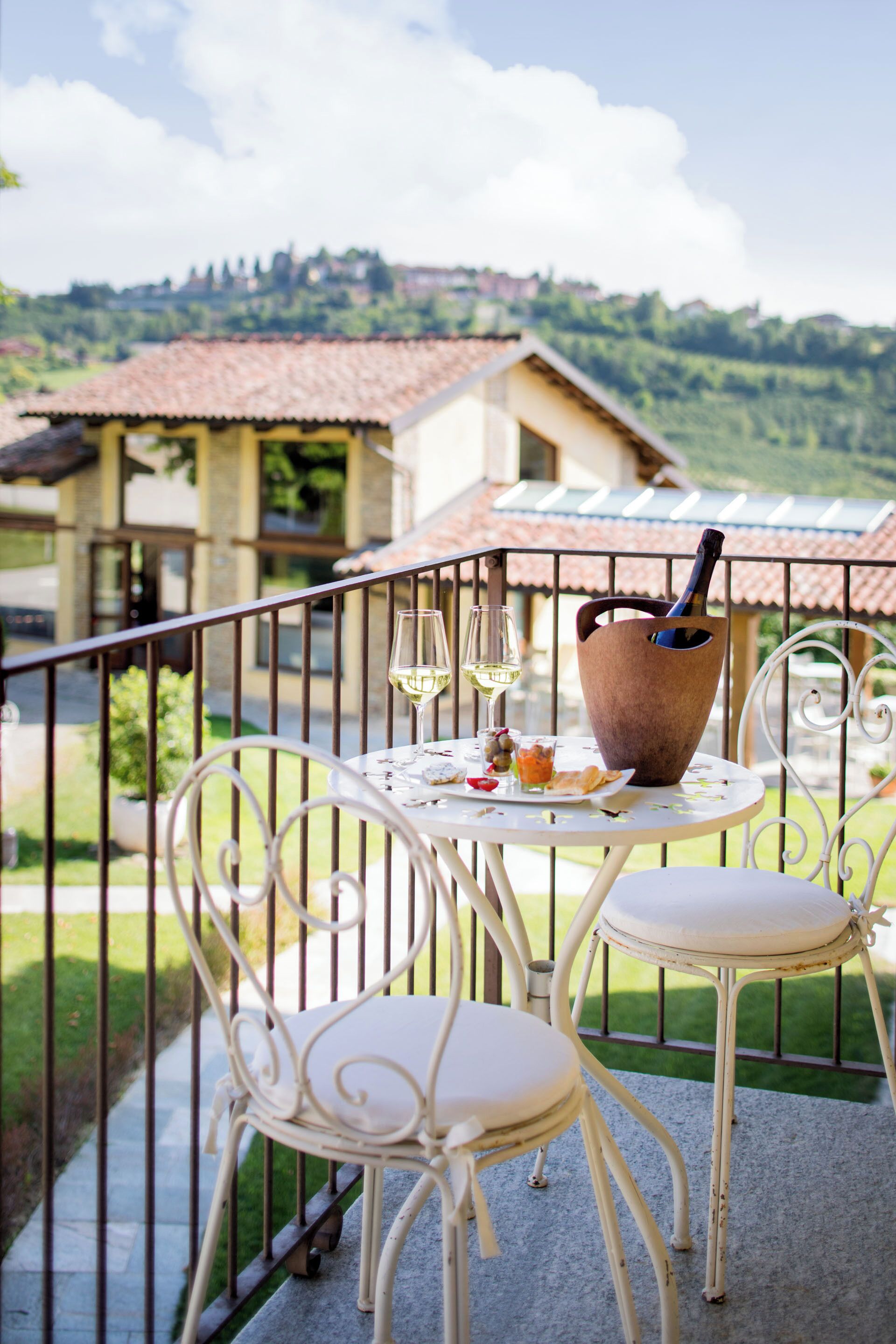 Un balcon avec une table dressée pour deux personnes, un verre à vin et une bouteille de vin.
