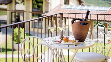 Un balcon avec une table dressée pour deux personnes, un verre à vin et une bouteille de vin.