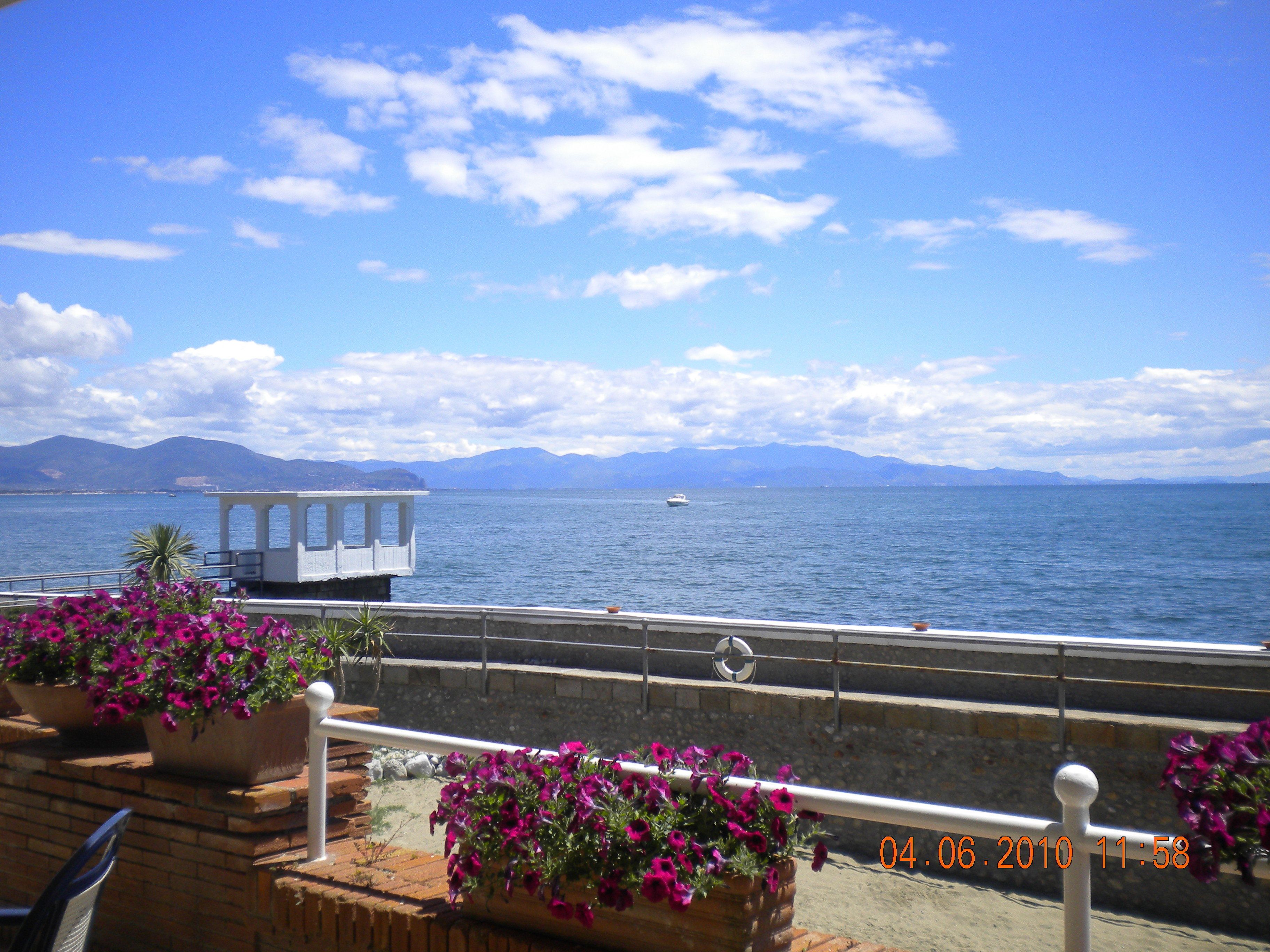 A coastal view with a gazebo, flower planters, and a railing.