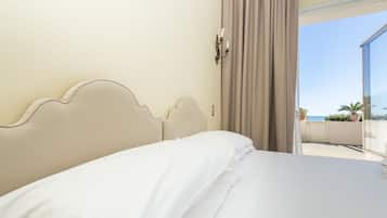 Una habitación de hotel con una cama, una ventana con cortinas y vistas al mar.