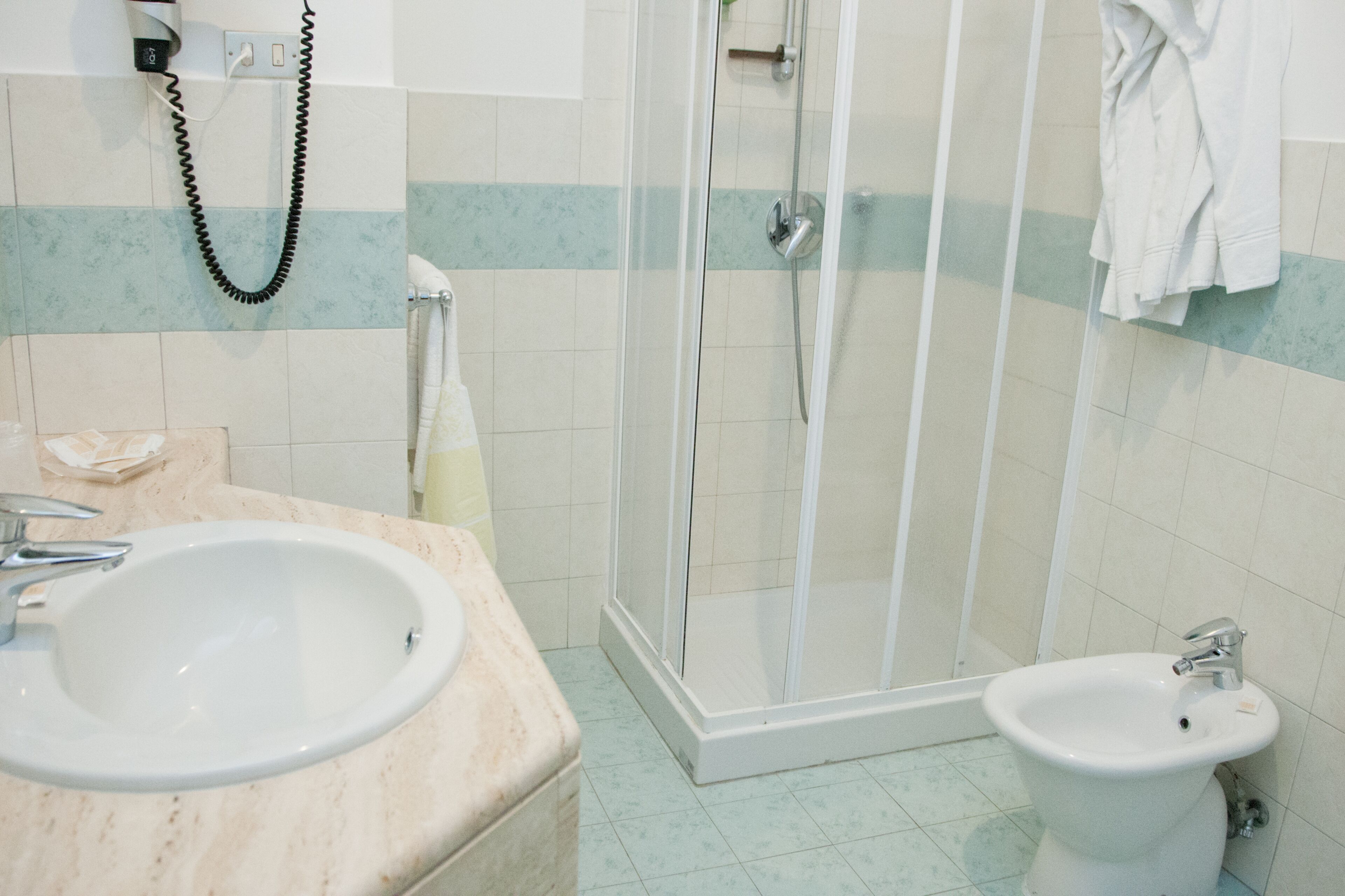 Et badeværelse med vask, bidet og bruser.