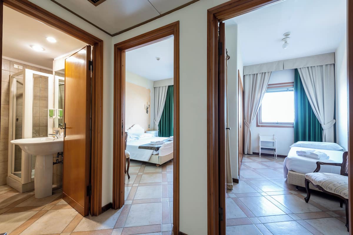 Ein Hotelzimmer mit Bad, einem Bett, einem Sessel und einem Fenster mit Vorhängen.