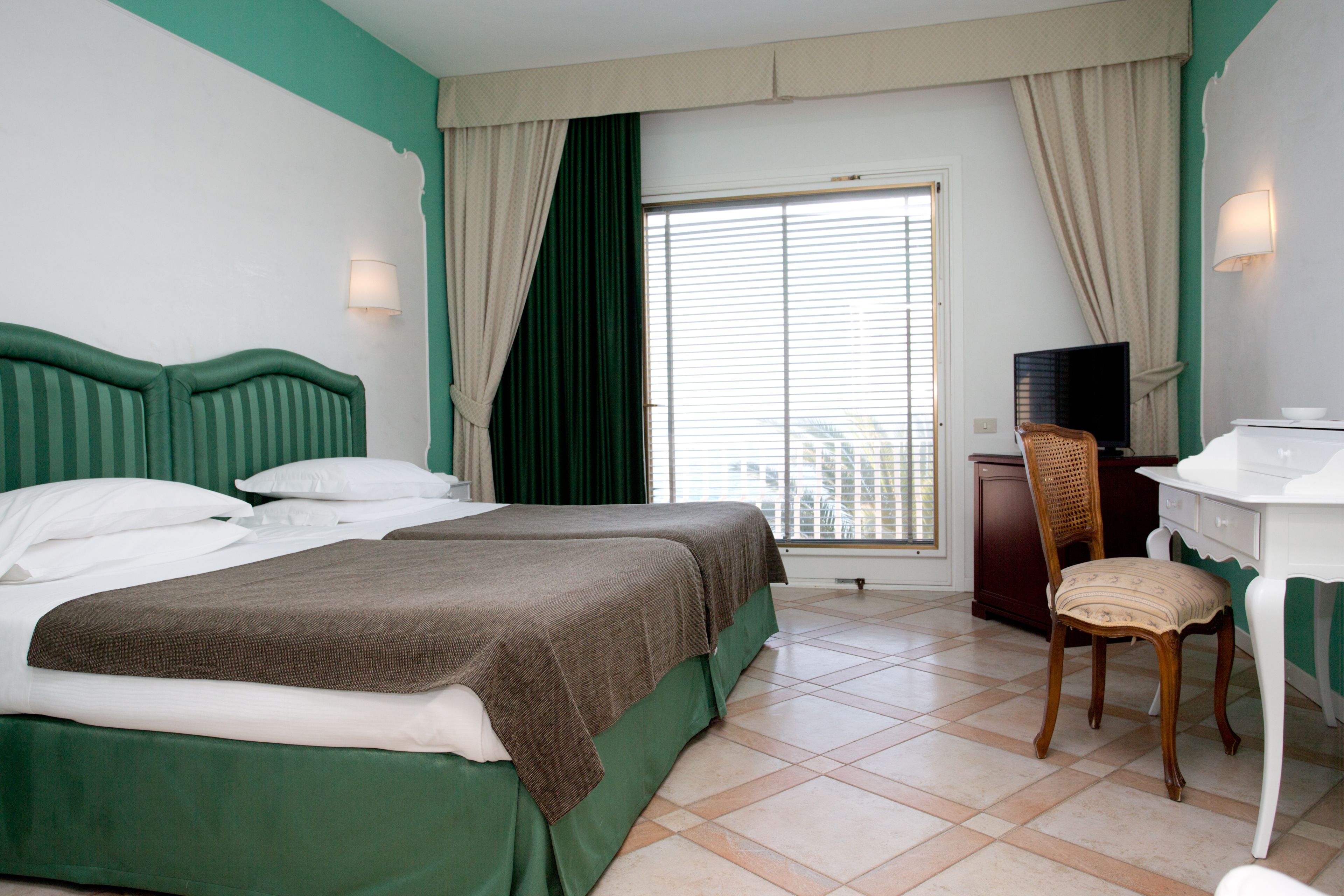 Ein Hotelzimmer mit zwei Betten, einem Schreibtisch, einem Stuhl und einem Fernseher.