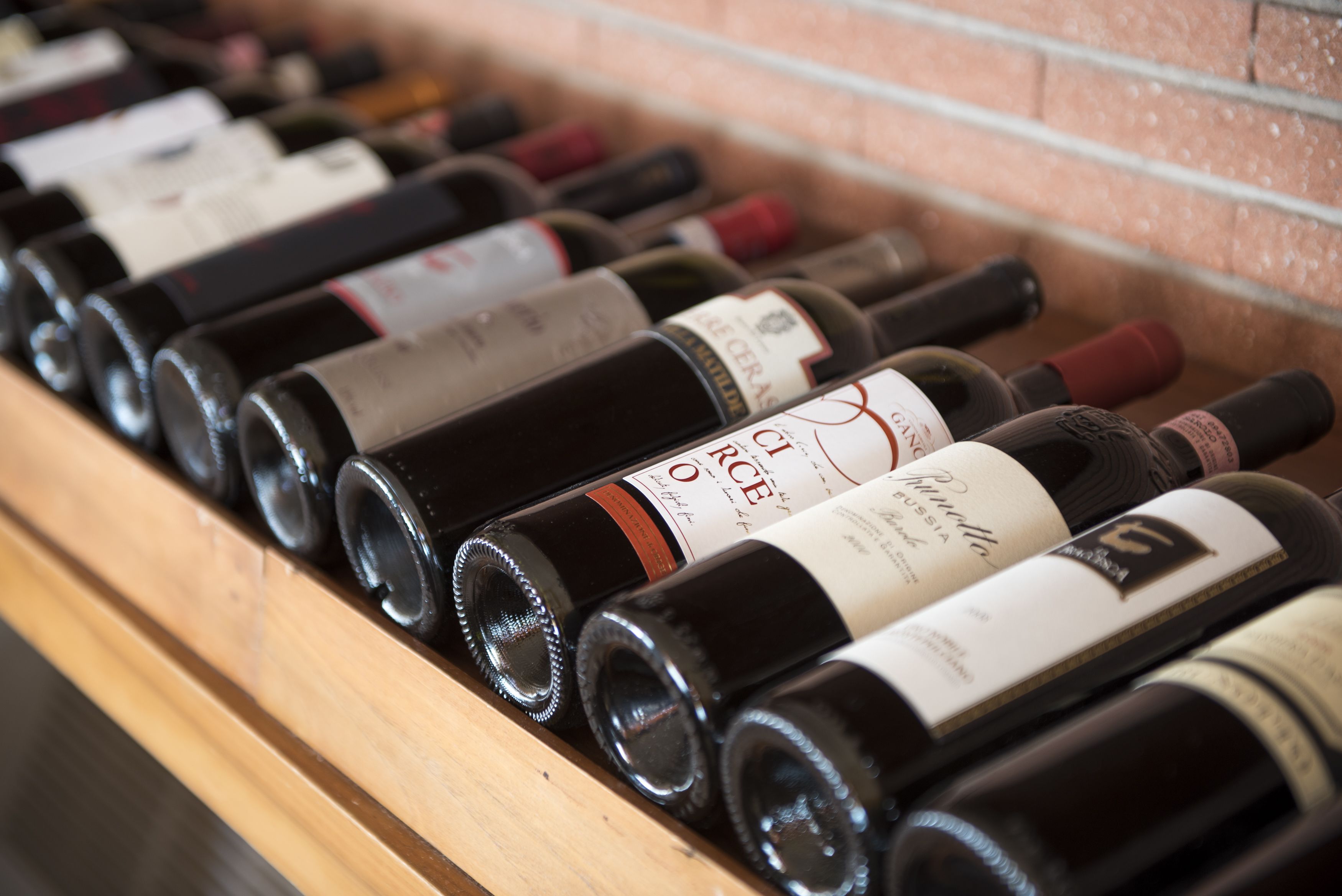 A wooden rack holding several wine bottles with labels.