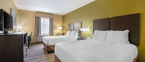 Una habitación de hotel con dos camas, un escritorio con televisor y una ventana con cortinas.