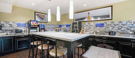 A modern kitchen with a central island, bar stools, and a dining table.