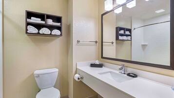 Ein Badezimmer mit Toilette, Waschbecken, Spiegel und Regalen mit Handtüchern.