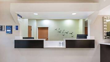 A reception area with a modern design, featuring a reception desk, a wall-mounted sign, and a decorative wall art of birds.