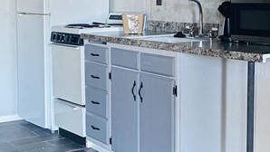 A kitchen with grey cabinets, a white refrigerator, a stove, a microwave, and a granite countertop. - Ocean Shores Inn & Suites (Ocean Shores)