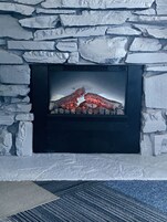 Una chimenea de piedra con marco negro, con leña ardiendo.