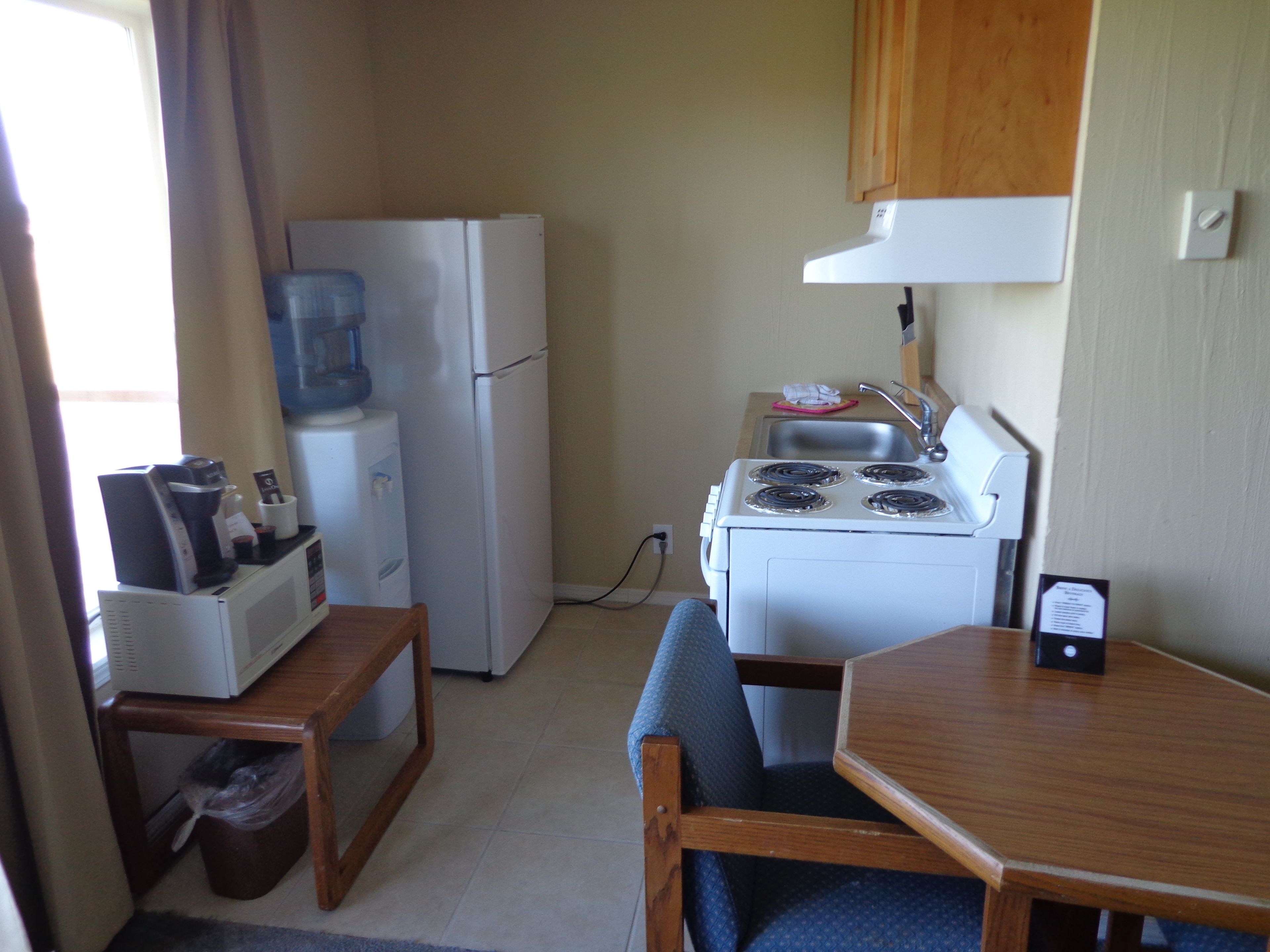 A compact kitchenette with a refrigerator, stove, sink, and a small table with chairs.