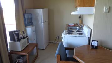 A compact kitchenette with a refrigerator, stove, sink, and a small table with chairs.