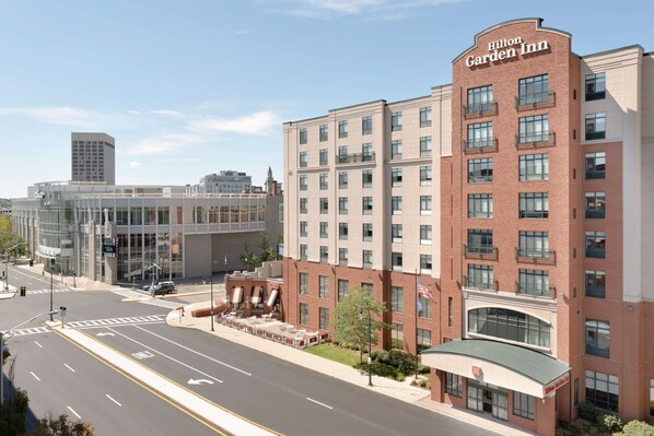 A Hilton Garden Inn with a modern brick facade, multiple balconies, and a glass entrance.