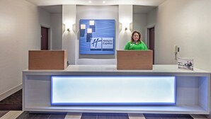 A hotel reception desk with a modern design, featuring a nameplate, a digital display, and a reception area. - Holiday Inn Express & Suites Shreveport South Park Plaza by IHG (Shreveport)