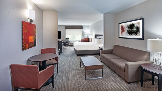 Quarto de hotel com cama, sofá, mesa de jantar e pequena escrivaninha.