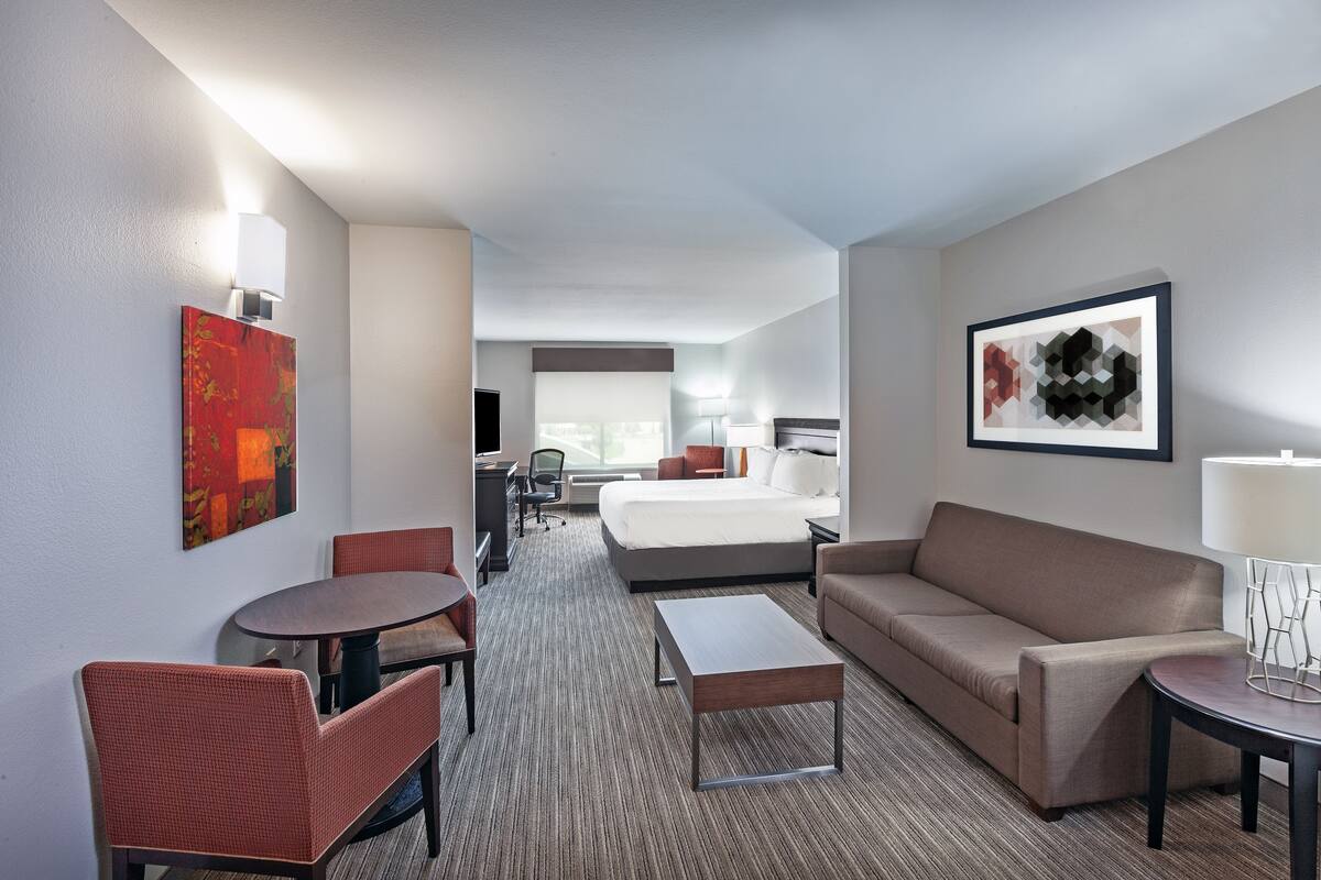 Une chambre d’hôtel comprenant un lit, un canapé, une table à manger et un petit bureau.