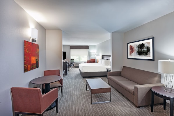 Una habitación de hotel con una cama, un sofá, una mesa de comedor y un escritorio pequeño.