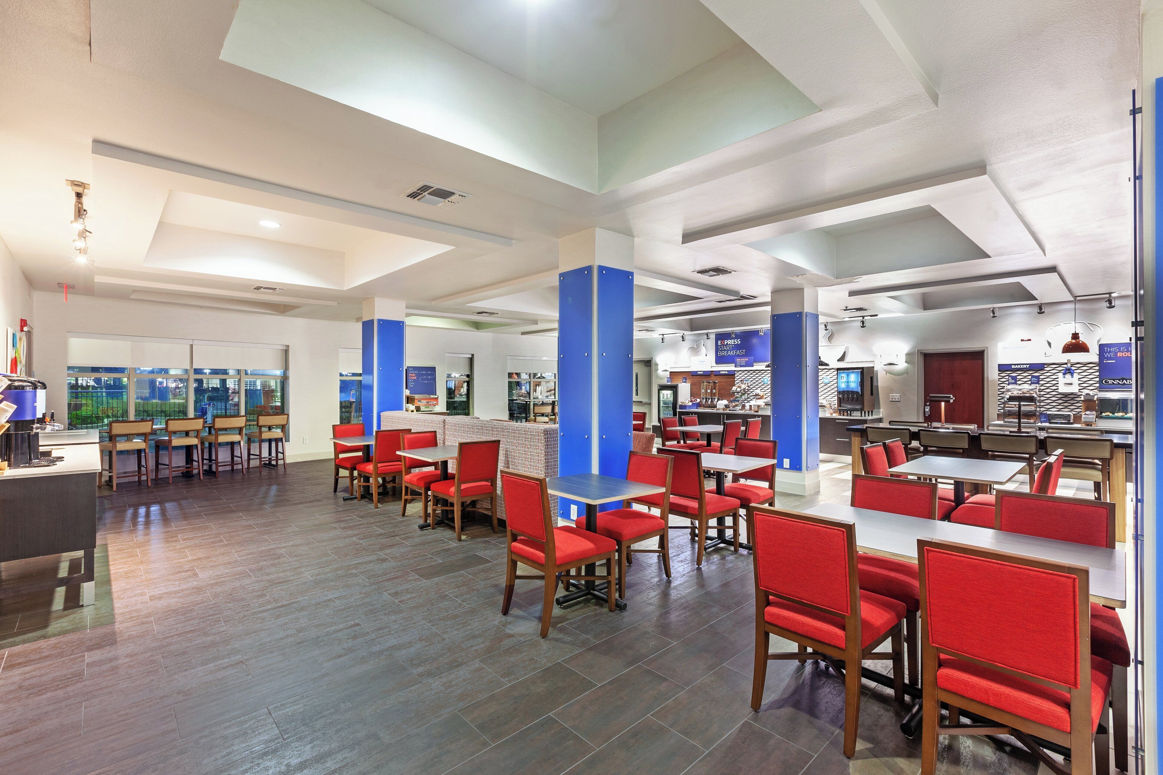 A spacious restaurant with high ceilings, red upholstered chairs, and a variety of seating arrangements.