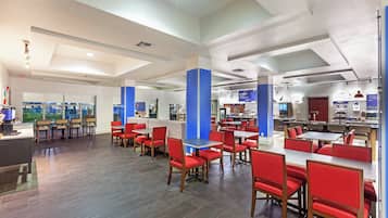 A spacious restaurant with high ceilings, red upholstered chairs, and a variety of seating arrangements.