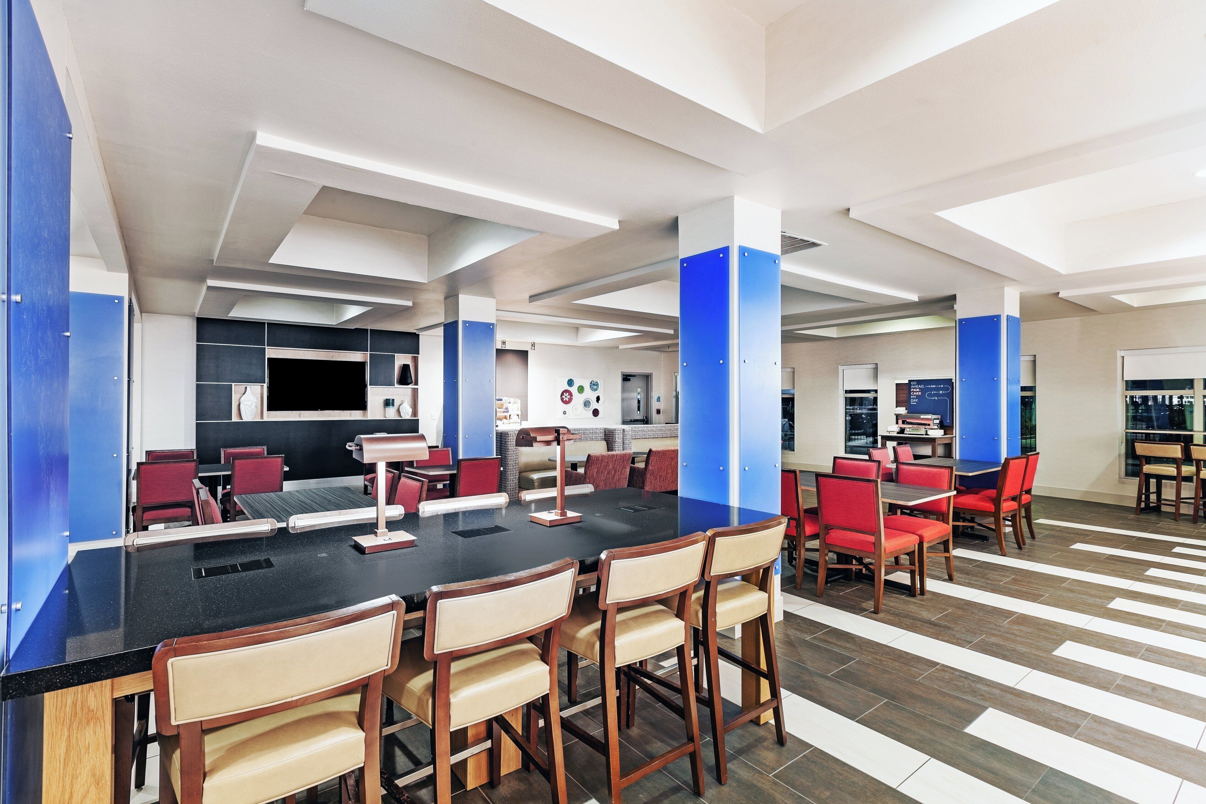 A modern conference room with a long table, red chairs, and a blue accent wall.