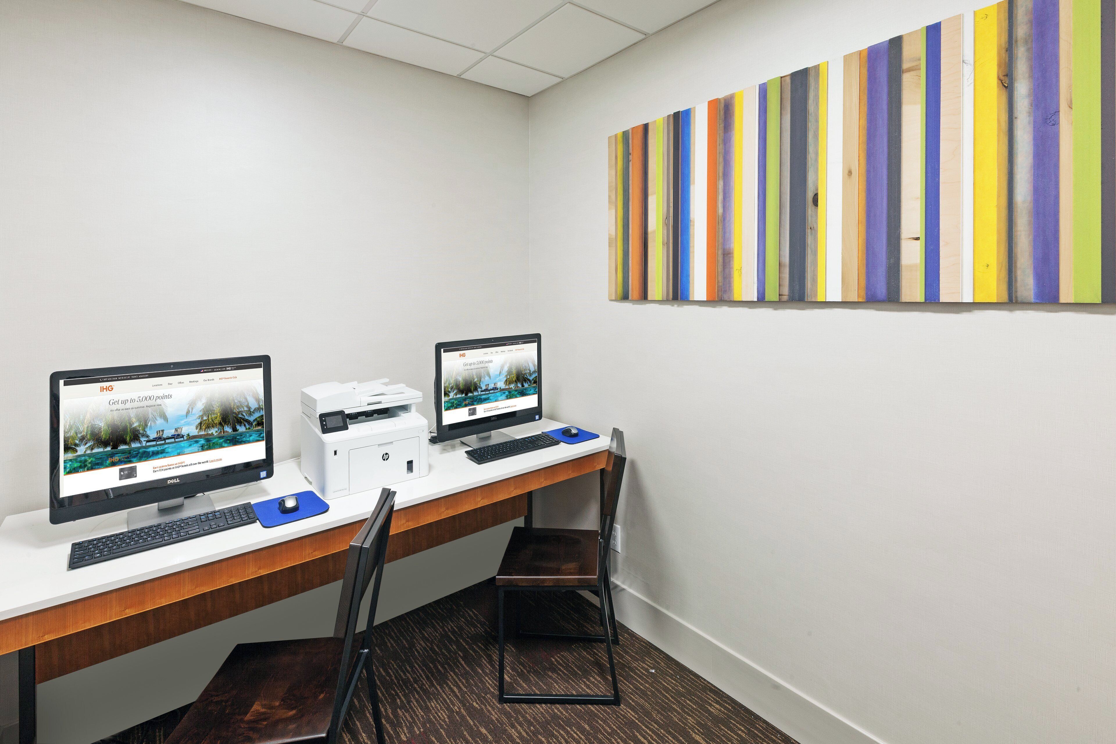 Un espace de travail équipé de deux ordinateurs de bureau, d’une imprimante et d’une chaise.