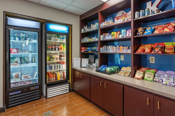 A snack bar with refrigerated and non-refrigerated sections, shelves stocked with snacks and beverages, and a clean, tiled floor.