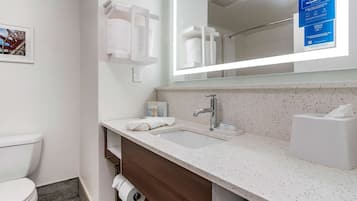 Un baño moderno con un inodoro blanco, un lavabo con un espejo encima y un perchero para toallas.