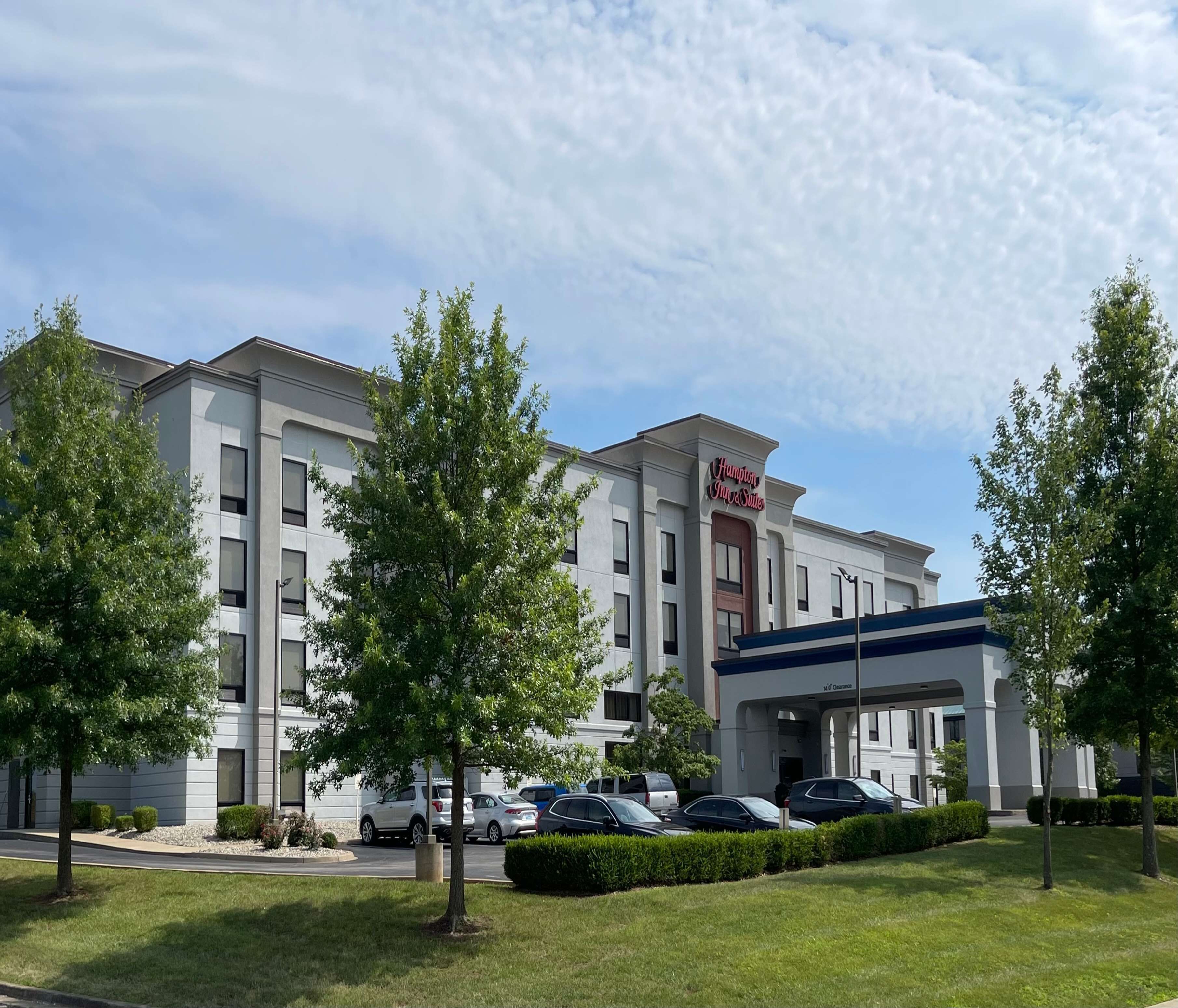 Un hotel moderno con un letrero llamativo de Hampton Inn & Suites.