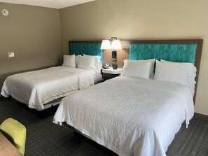 A hotel room with two single beds, a nightstand with a lamp, and a small seating area. - Hampton Inn & Suites Louisville East (Louisville)