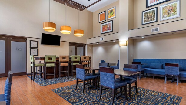 A hotel lobby with a dining area, seating, and artwork on the walls. - Hampton Inn & Suites Louisville East (Louisville)