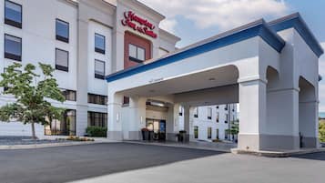 Un hotel Hampton Inn & Suites con entrada accesible, zona de estacionamiento techada y fachada bien conservada.