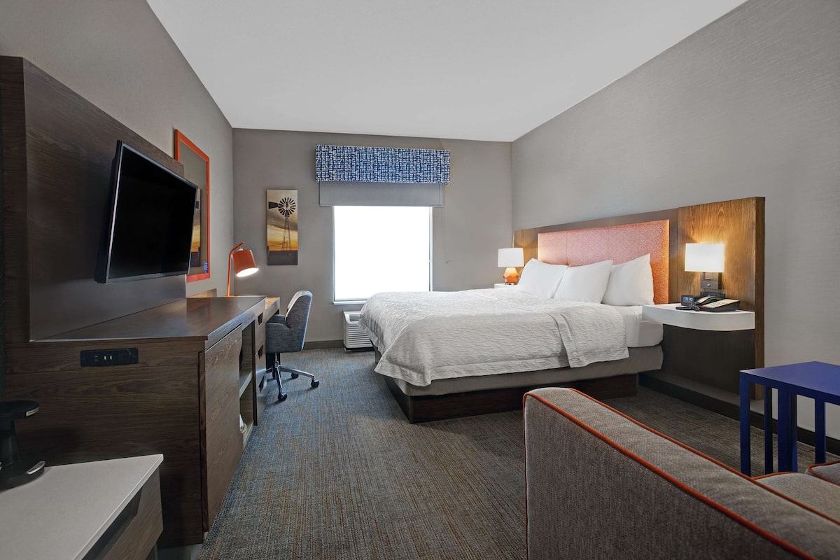 A hotel room with a bed, desk, TV, and a window with a view.