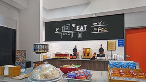 A breakfast buffet area with a sign reading "EAT HERE" and various food items like cereal and pastries. - Hampton Inn Keokuk (Keokuk)