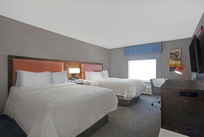 A hotel room with two beds, a desk, a chair, a TV, and a window with a view.