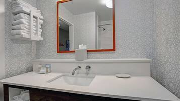 A modern bathroom with a white sink, a large mirror with a red frame, and a towel rack.