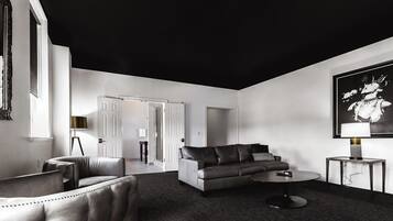 Un salon moderne avec un plafond sombre, un canapé gris, une table basse ronde et un tableau accroché au mur.