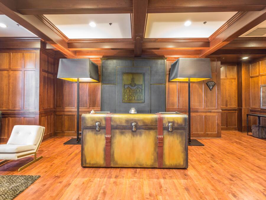 Un vestíbulo con un mostrador de recepción de estilo vintage, paneles de madera y una silla de cuero blanco.