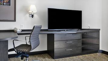 Une chambre d’hôtel équipée d’un bureau, d’une chaise, d’un téléviseur à écran plat, d’une lampe et d’un téléphone.
