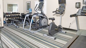 A gym with treadmills, elliptical machines, and dumbbells.