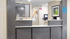 A reception desk with a computer, a framed picture, and a bulletin board.