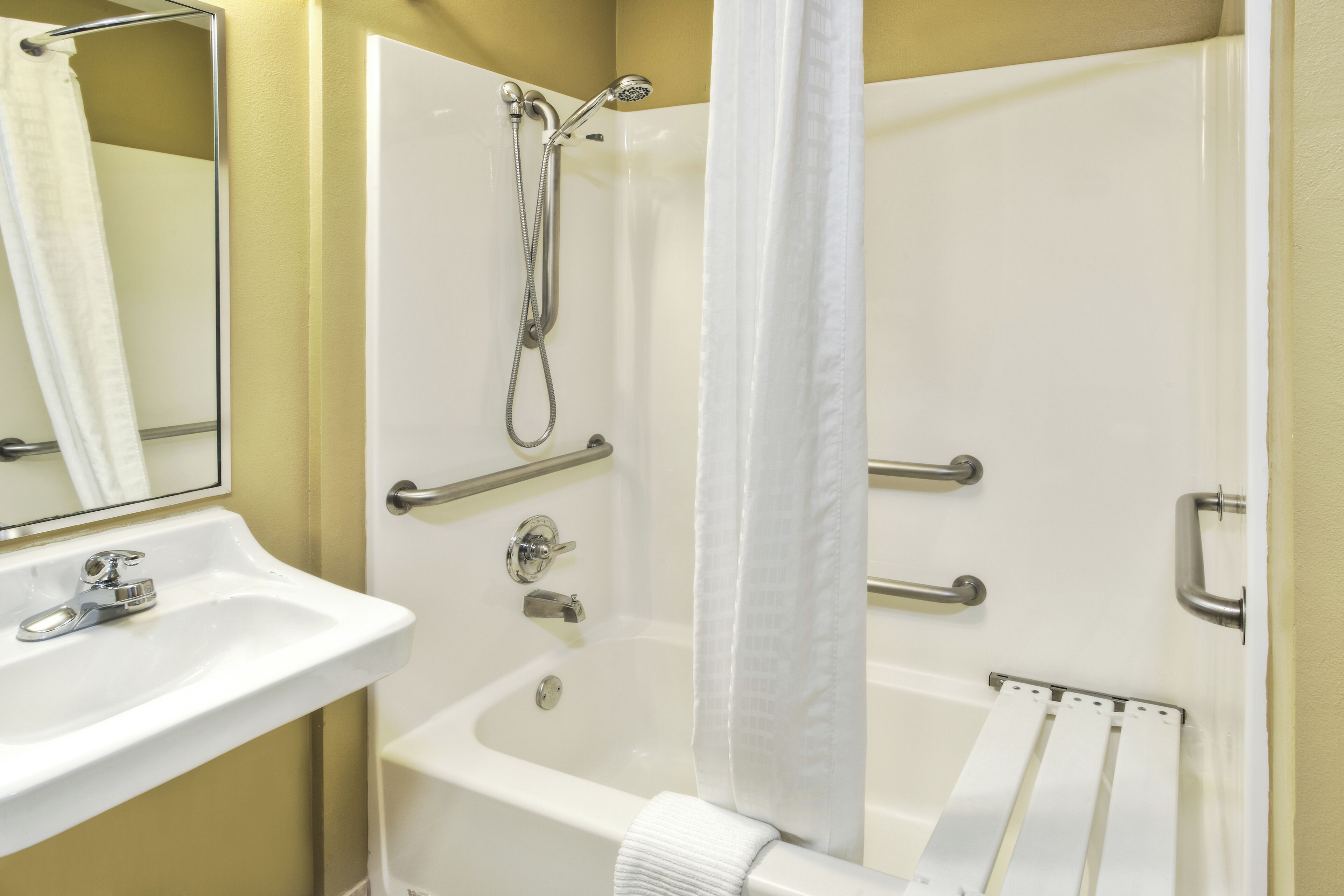 A bathroom with a sink, a shower with a handheld showerhead, and a towel rack.