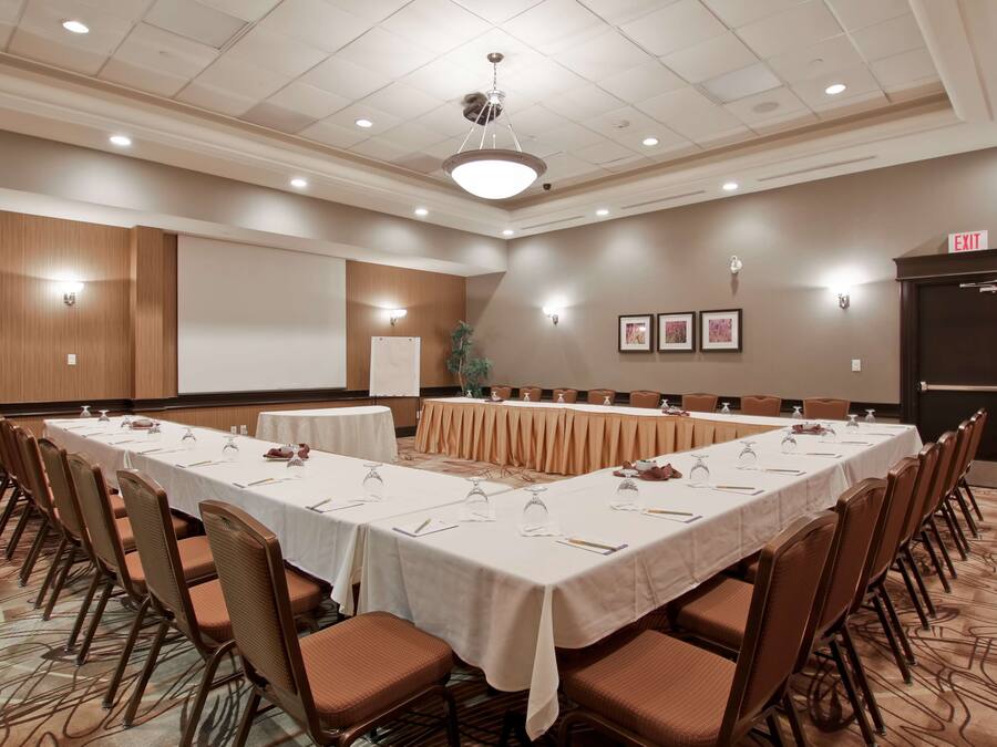 Un salón de conferencias con una larga mesa, sillas, una pantalla de proyector y una señal de salida.