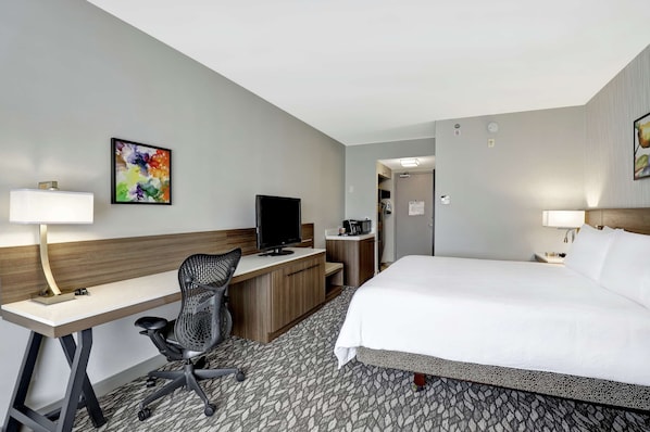 A hotel room with a bed, desk, chair, television, and artwork on the walls. - Hilton Garden Inn Toronto/Ajax (Ajax)