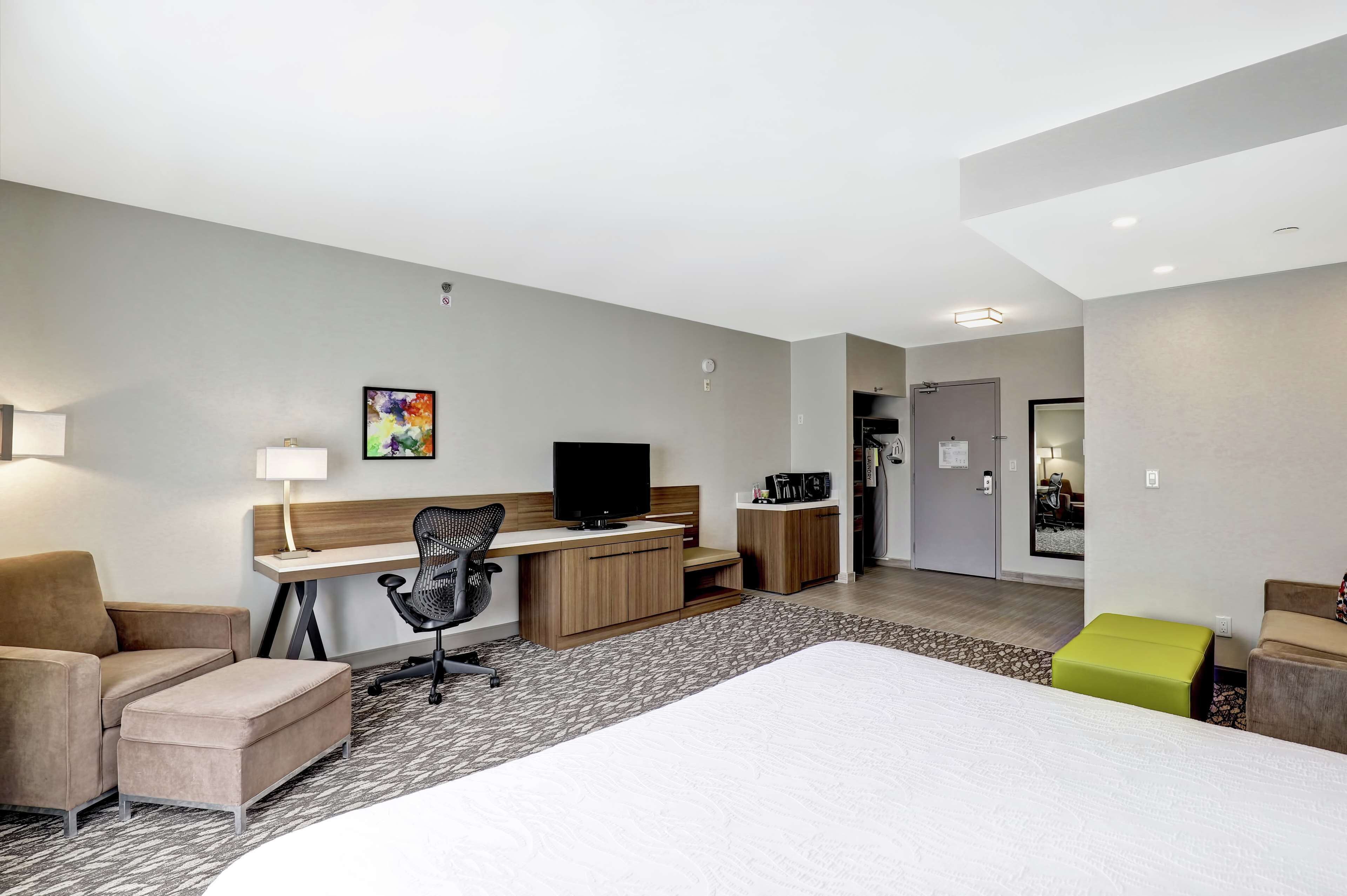 A hotel room with a bed, desk, chair, and a television.