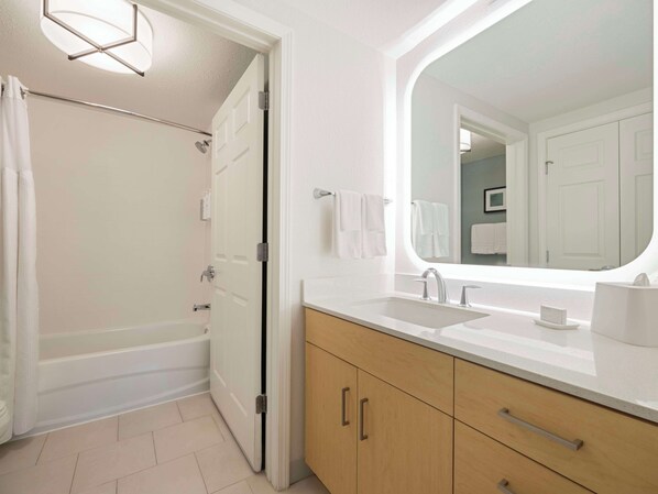 Un baño moderno con bañera, lavamanos y un espejo grande.