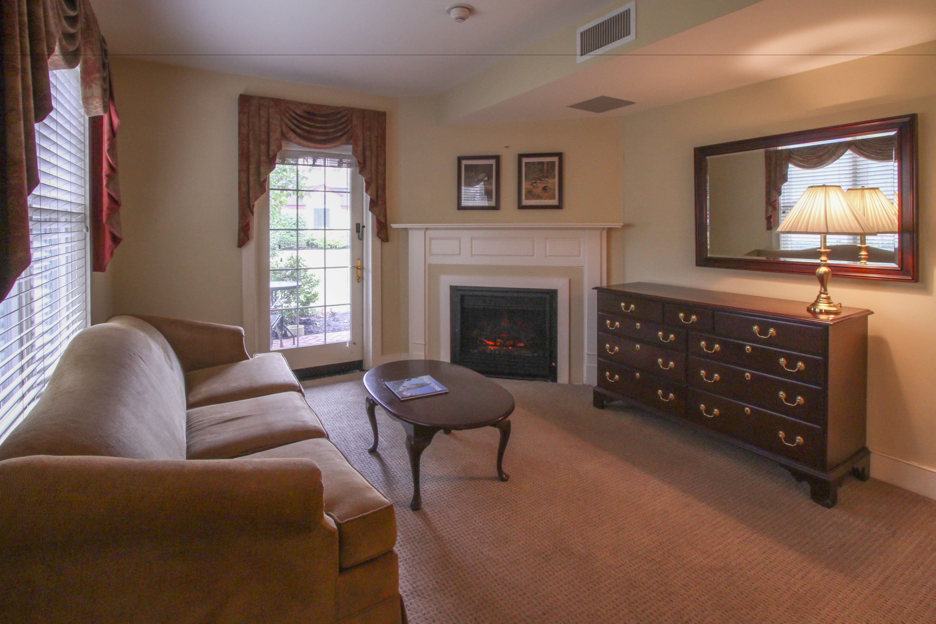 A living room with a fireplace, a sofa, a dresser, and a lamp.