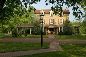A stone building with a red roof, a covered entrance, and a well-maintained lawn.