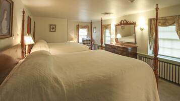 A hotel room with two beds, a dresser, a mirror, and a window with curtains.
