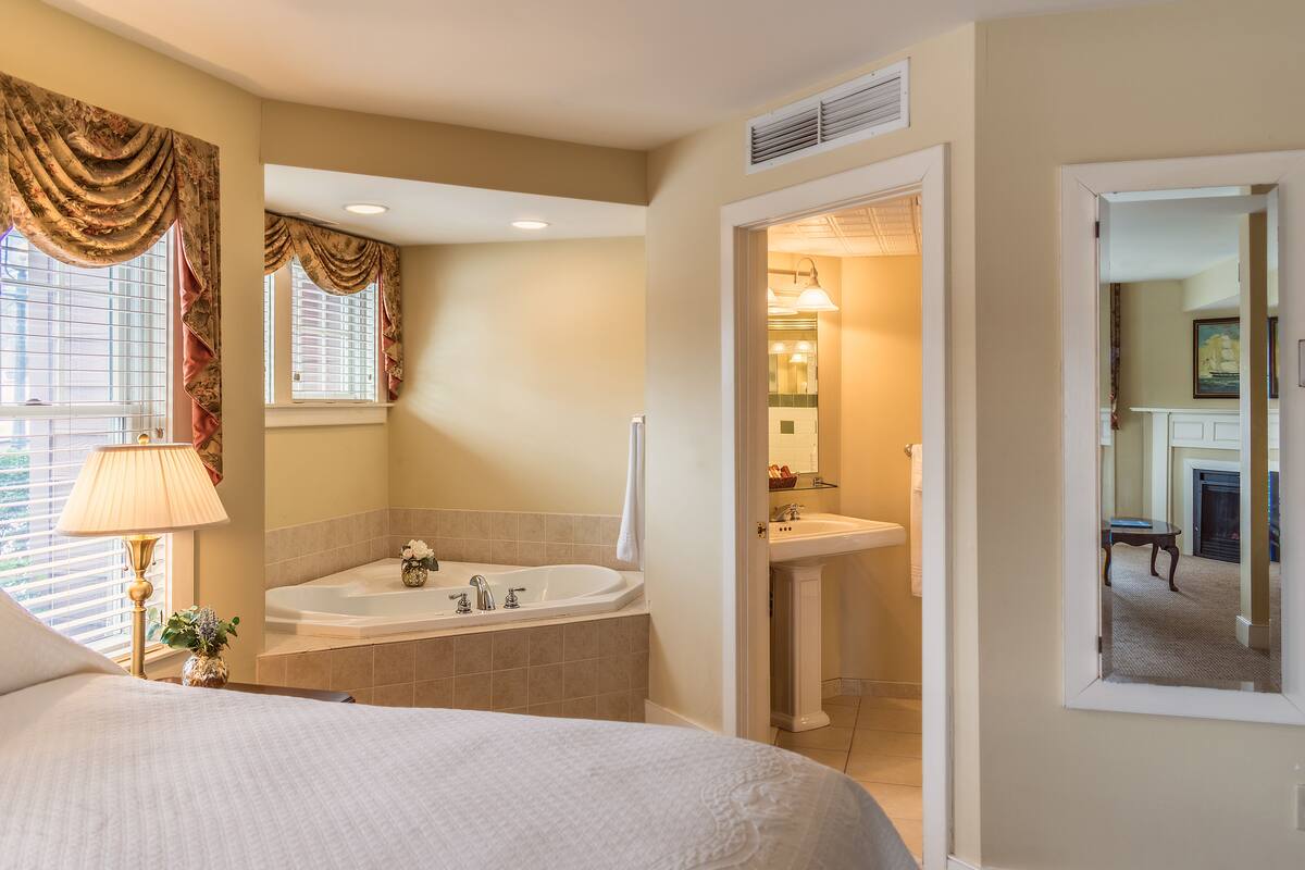 Ein Schlafzimmer mit einem großen Bett, ein Badezimmer mit Badewanne und Waschbecken sowie ein Flur, der zu einem Essbereich führt.
