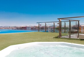 Tagpool med jacuzzi, klart himmel og udsigt over bybilledet.